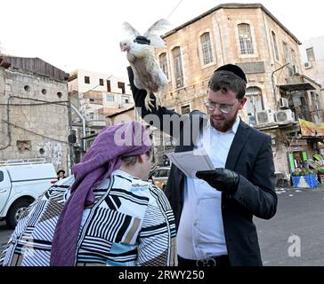 Gerusalemme, Israele. 21 settembre 2023. Un ebreo ortodosso alza un pollo sulla testa di sua moglie durante l'antico rituale Kapparot a Mea Shearim a Gerusalemme, giovedì 21 settembre 2023. Il Kapparot è preformato prima dello Yom Kippur, il giorno dell'Espiazione, il giorno più sacro del calendario ebraico, e trasferisce simbolicamente i peccati dell'anno passato al pollo. Foto di Debbie Hill/ Credit: UPI/Alamy Live News Foto Stock