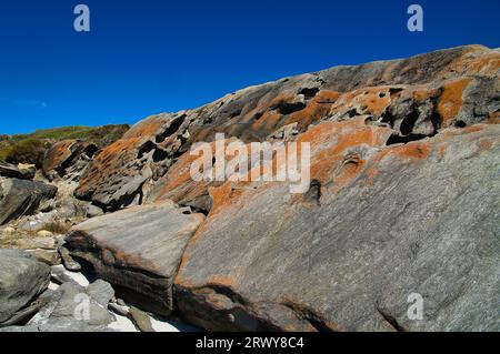 Rocce erose, ricoperte di licheni arancio-marrone, sulla remota costa di Hamersley Beach nel Fitzgerald River National Park, Australia Occidentale Foto Stock