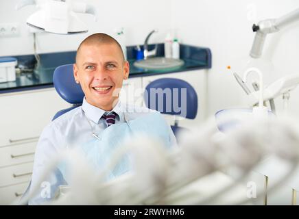 Sorridente uomo soddisfatto paziente visita dentista Foto Stock