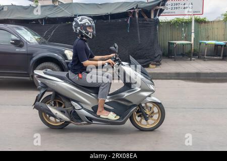 SAMUT PRAKAN, THAILANDIA, 19 settembre 2023, Una donna con un casco cavalca una moto in una strada cittadina Foto Stock