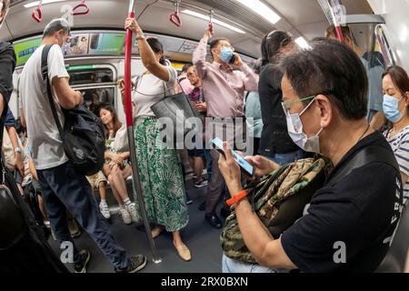 I passeggeri che utilizzano i telefoni cellulari su Hong Kong metropolitana MTR, Hong Kong, Cina. Foto Stock