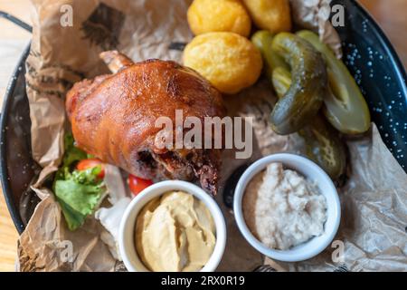 Gambo di maiale al forno servito con patate al forno, rafano, senape e cetrioli sottaceto. Piatto tradizionale polacco Foto Stock