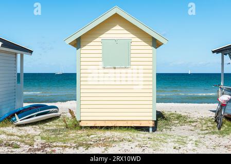 Vista frontale sul retro di una baita in legno giallo sulla spiaggia di Skanör med Falsterbo al Öresund al sole del mattino, Skåne, Svezia Foto Stock