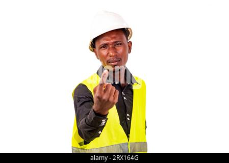 Giovane ingegnere che indossa un giubbotto verde e un casco di sicurezza bianco mentre mostra il gesto di Vieni qui con il dito indice. Foto Stock