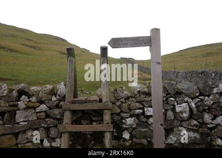 Wooden Ladder stile & Signpost for Public Footpath to High Hill Lane on Stockdale Lane vicino Settle nello Yorkshire Dales National Park, Inghilterra, Regno Unito. Foto Stock