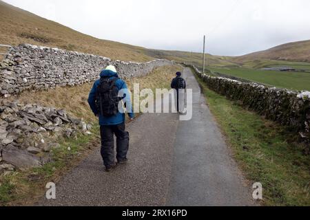 Due uomini (escursionisti) a piedi su Stockdale Lane vicino a Settle nel Parco nazionale Yorkshire Dales, Inghilterra, Regno Unito. Foto Stock