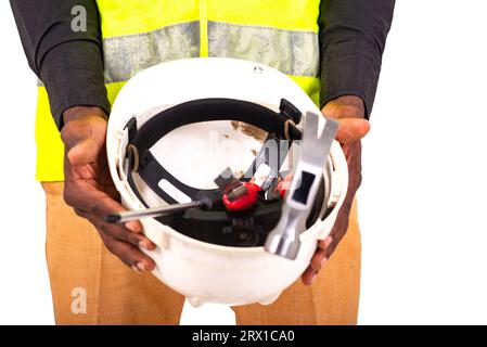 mani di un giovane tecnico che indossa un giubbotto verde che mostra un casco di sicurezza con gli attrezzi all'interno. Foto Stock