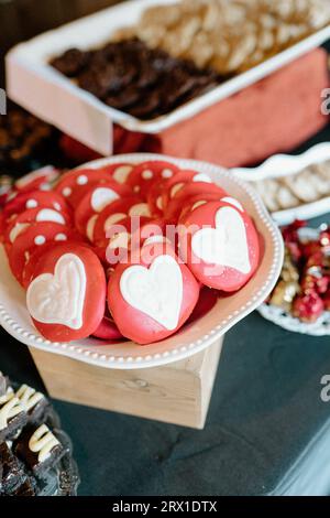 Assortimento di biscotti a base di cuore sul tavolo da dessert; tema rosso e bianco Foto Stock