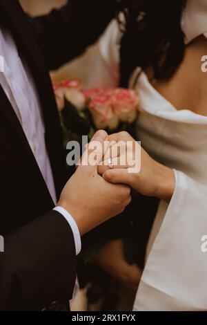 Primo piano della coppia fidanzata con anello diamantato e bouquet. Foto Stock