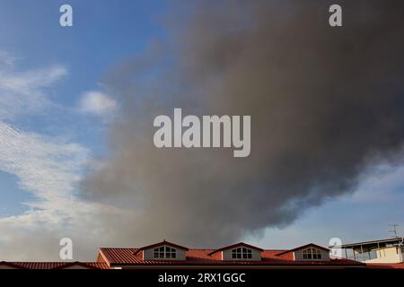 Un fumo spesso ricopre parte del cielo sul tetto Foto Stock