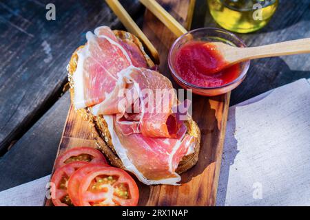 Vista dall'alto di una tipica colazione spagnola con pane tostato con olio d'oliva vergine, pomodoro e prosciutto iberico alimentato a ghianda Foto Stock