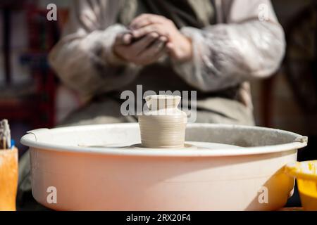 un maestro vasaio crea un vaso di argilla su una ruota di argilla fatta di argilla Foto Stock