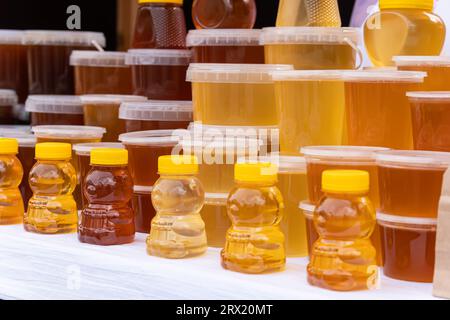 Ci sono molti barattoli di miele biologico e naturale in vendita. Miele diverso, diversi colori in lattine di plastica sono pronti per la vendita al miele f Foto Stock