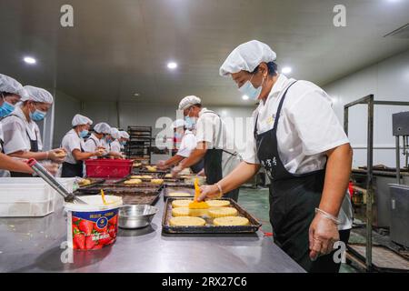 Contea di Luannan, Cina - 8 settembre 2022: Il lavoratore sta oliando la pelle di torta lunare per la cottura. Foto Stock