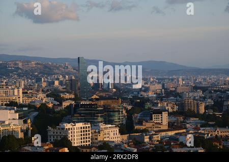 Vista mattutina della capitale della Georgia - Tbilisi. Tetti di case, chiese e grattacieli. Vista dall'alto dalla fortezza della città vecchia Foto Stock