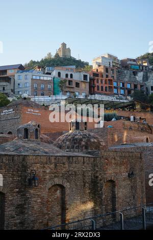 Lo storico quartiere della città vecchia nel centro di Tbilisi. La capitale georgiana al mattino in una giornata di sole. Splendidi edifici in mattoni e tetti a cupola Foto Stock