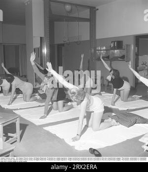 Ginnastica in passato. In una palestra, un gruppo di donne si inginocchiano e allungano le braccia in un movimento. Le giovani donne si prendono una pausa dal lavoro e fanno ginnastica durante l'orario di lavoro. La ginnastica da ufficio era un'invenzione moderna negli anni '1940, quando l'assistenza sanitaria per i dipendenti cominciò ad essere implementata. Svezia 1949. Kristoffersson rif. AX72-7 Foto Stock