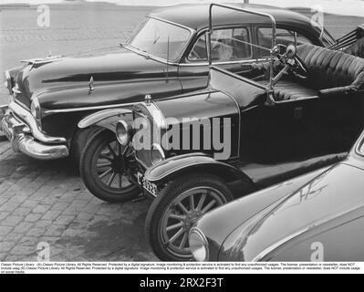 Negli anni '1950 Le auto sono parcheggiate l'una accanto all'altra e provengono da epoche diverse. Una Oldsmobile americana, modello CA 1951-1952 e una Model T Ford. Svezia 1957 Foto Stock