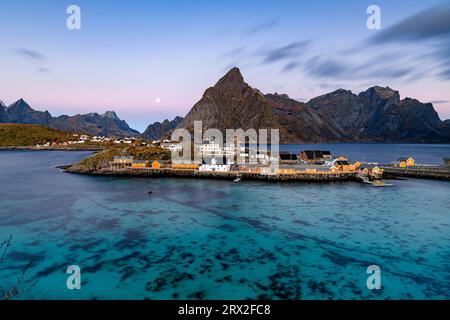 Alba sul monte Olstind e villaggio di pescatori di Sakrisoy, affacciato sul mare blu freddo, sulle isole Lofoten, sul Nordland, sulla Norvegia, sulla Scandinavia, Europa Foto Stock