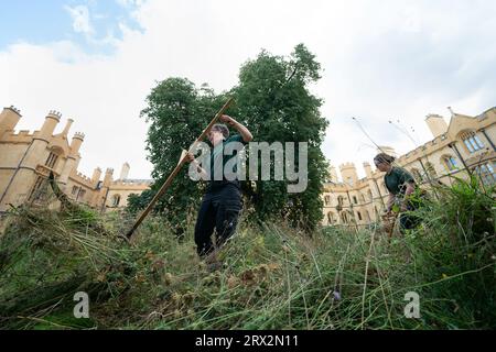 Il giardiniere di Trinity Dr Jo Miles e il collega professore di Trinity Marian Holness falciarono fiori selvatici nel Meadow Circle presso il XIX secolo New Court del Trinity College di Cambridge. La falciatura, o falciatura, è una tradizione secolare che si ritiene sia stata praticata a Trinity prima dei rasaerba. Data immagine: Venerdì 22 settembre 2023. Foto Stock