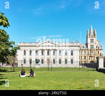 Un paio di studentesse siedono sul prato all'esterno della prestigiosa cappella del King's College e di fronte alla camera del Senato dell'università di Cambridge, Ing Foto Stock