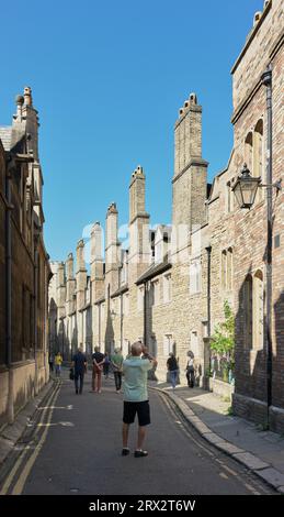 I turisti in una strada stretta guardano i vasi del camino del prestigioso college di Trinity presso l'università di Cambridge, in Inghilterra. Foto Stock