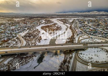 Il ponte e l'incrocio sul fiume Selenga ghiacciato nella città siberiana di Ulan-Ude, Buryatiya, Russia, con vista panoramica aerea durante il Foto Stock