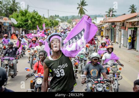 I sostenitori del partito di opposizione della Tanzania, ACT Wazalendo tengono le bandiere del partito su una motocicletta durante il loro raduno politico nel distretto di Kilwa, Lindi reg Foto Stock
