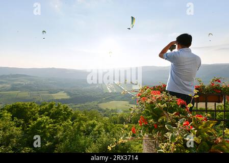 Un turista fotografa i parapendio dalla cima del villaggio collinare di Motovun, Istria, Croazia, Europa Foto Stock