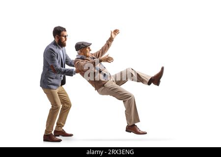 Uomo più giovane che cattura un uomo anziano che cade isolato su sfondo bianco Foto Stock