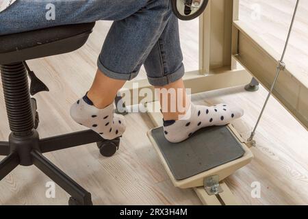 Piedi femmina sul pedale di una macchina da cucire, primo piano del motore Foto Stock