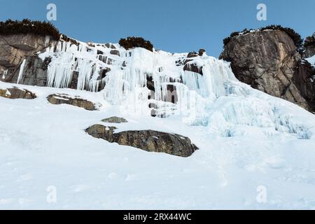 Cascata ghiacciata Skok in alta Tatra (Slovacchia) in inverno. Grande cascata con ghiaccio gigante blu sulle rocce. Foto Stock