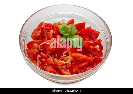 Insalata di pomodori crudi tagliati con fette di cipolla condita con olio d'oliva e foglie di basilico in una ciotola di vetro isolata su bianco, percorso di ritaglio incluso Foto Stock