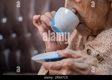 vecchia che beve caffè in salotto Foto Stock