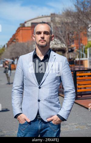 In vita, ritratto verticale di un uomo caucasico adulto con abito elegante, barba e capelli corti, in piedi all'aperto a Puerto Madero Argentina, calma con han Foto Stock