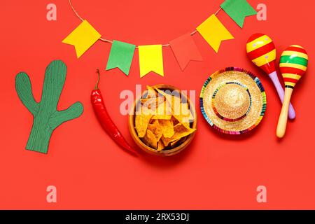 Composizione con simboli messicani e nachos per il giorno dell'indipendenza su sfondo rosso Foto Stock