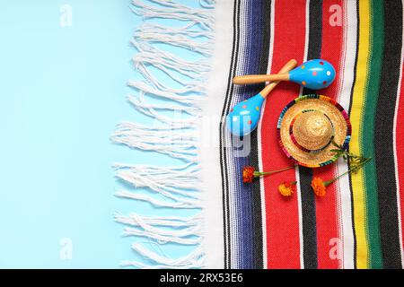 Poncho con fiori, cappello sombrero e maracas messicane per il giorno dell'indipendenza su sfondo blu Foto Stock