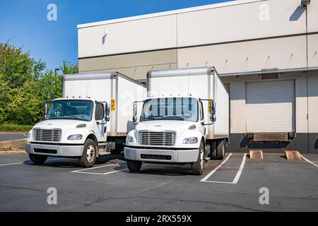 Semi-carri da lavoro standard per impieghi medi con cabina corta bianca con rimorchi scatolati per consegne locali ed esigenze di piccole imprese in magazzino Foto Stock