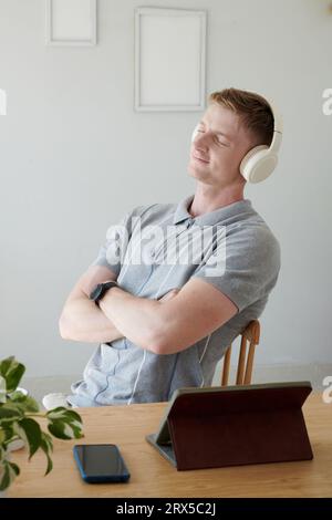 Un giovane sorridente mentre ascolta la sua canzone preferita con le cuffie Foto Stock