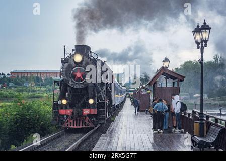 Sortavala, Russia - 15 luglio 2023: Il treno a vapore retrò si avvicina alla piattaforma di legno. Foto Stock