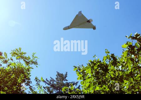 Shahed drone da combattimento che vola sullo sfondo di fan e cielo della città, vista dal basso, attacco droni, guerra in Ucraina, rendering 3d. Foto Stock