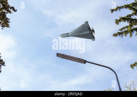 Drone da combattimento Shahed che sorvola il cielo e il fan della città, vista dal basso, attacco di droni su strutture e infrastrutture elettriche, guerra in Ucraina, rendering 3d. Foto Stock