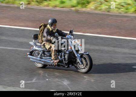 Triumph moto Mirroring della moto  riflesso del veicolo su strada bagnata; viaggia a velocità sostenuta sull'autostrada M6 a Greater Manchester, Regno Unito Foto Stock