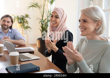 Gli uomini d'affari multiculturali battono le mani per concludere una riunione di gruppo nella sala riunioni Foto Stock