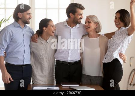 Gli uomini d'affari diversi che accolgono si sentono felicissimi di celebrare il successo comune dell'azienda Foto Stock
