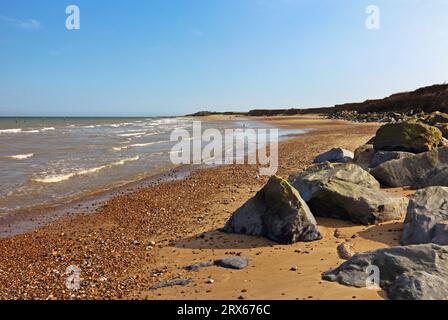 Una vista lungo la costa da difese rocciose e basse scogliere in una bella giornata autunnale sulla costa del Norfolk settentrionale a Happisburgh, Norfolk, Inghilterra, Regno Unito. Foto Stock