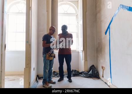 Architetto e costruttore discutono insieme in cantiere Foto Stock
