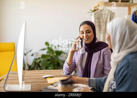 Felice wedding planner con un collega che parla sullo smartphone Foto Stock