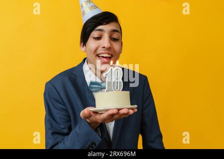 Buon uomo che soffia candela il 18° compleanno Foto Stock