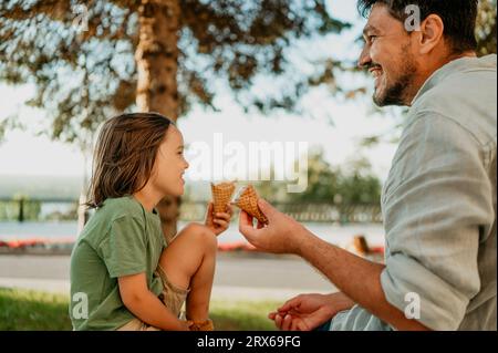 Buon padre e figlio che si godono i coni del gelato insieme Foto Stock